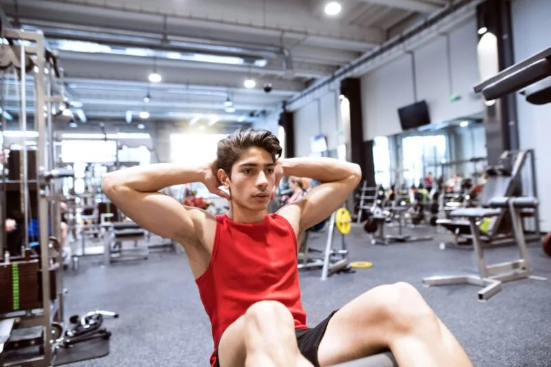 A man doing sit-ups in the gym, sore muscles after workout