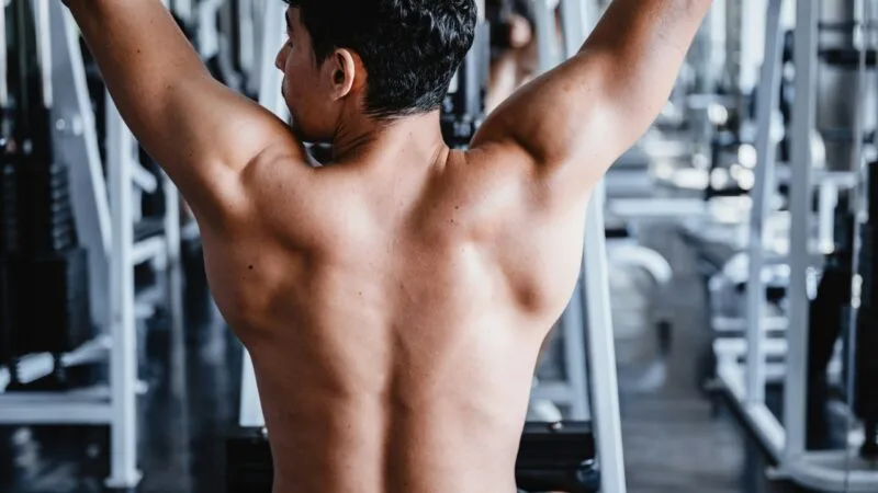 Back of a man in the gym, showing muscles, sore muscles after workout